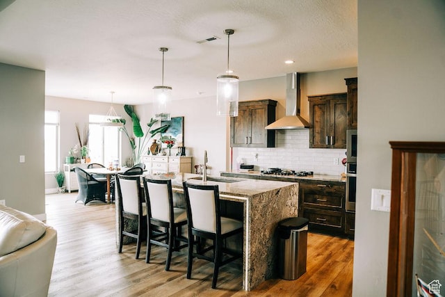 2366 W 3750 N, Cedar City, UT 84721 - kitchen featuring wall chimney exhaust hood, a sink, backsplash, light wood finished floors, and light stone countertops
