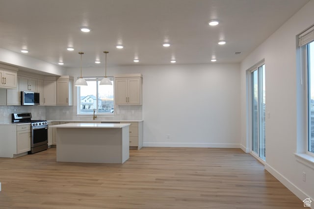 743 E 1250 S, Hyrum, UT 84319 - kitchen featuring appliances with stainless steel finishes, light wood finished floors, a center island, decorative backsplash, and light countertops