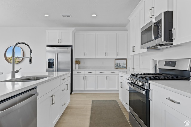 1445 N Arena Roja Dr, Washington, UT 84780 - kitchen with stainless steel appliances, a sink, recessed lighting, light wood finished floors, and white cabinets