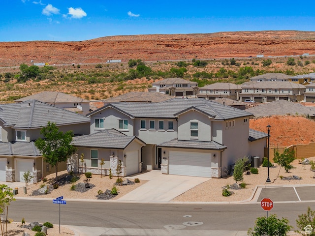 1445 N Arena Roja Dr, Washington, UT 84780 - view of front facade featuring an attached garage, stucco siding, concrete driveway, stone siding, and a mountain view