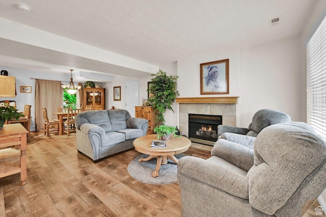 1076 E Creekside, Ogden, UT 84404 - living room with a tiled fireplace, light wood-style flooring, and a chandelier
