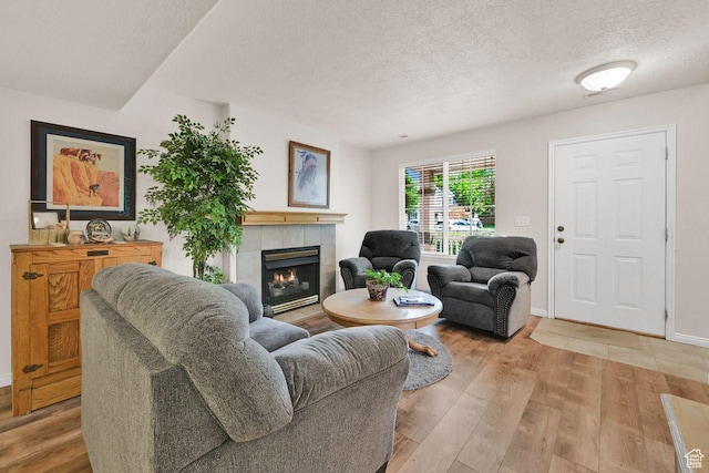 1076 E Creekside, Ogden, UT 84404 - living area with a textured ceiling, a tile fireplace, light wood-type flooring, and baseboards