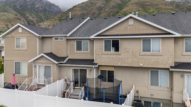 1298 S 1410 E, Provo, UT 84606 - back of property featuring stucco siding, a mountain view, roof with shingles, and a trampoline