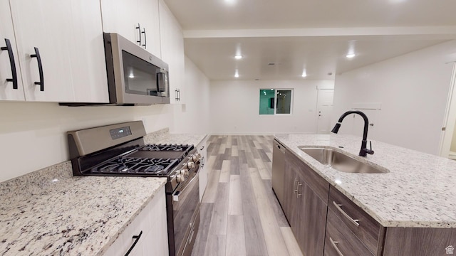 920 S 25 E # 18E, Cedar City, UT 84720 - kitchen with appliances with stainless steel finishes, a sink, light wood finished floors, white cabinets, and a center island with sink
