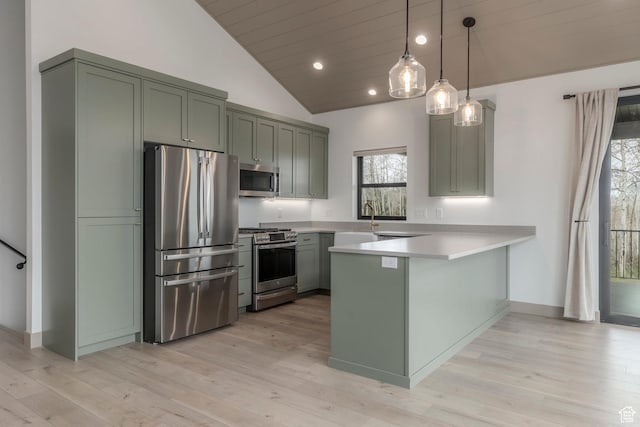 kitchen featuring appliances with stainless steel finishes, a peninsula, lofted ceiling, light countertops, and light wood-style flooring