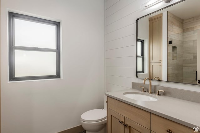 bathroom with vanity, toilet, and tiled shower