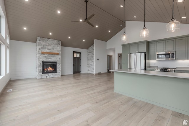 kitchen featuring appliances with stainless steel finishes, high vaulted ceiling, a ceiling fan, light countertops, and a stone fireplace