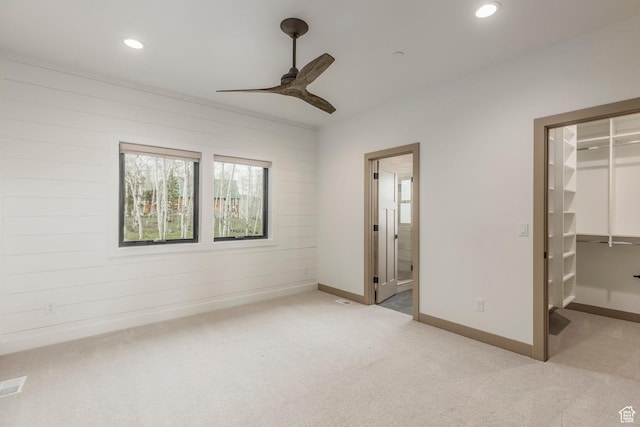 unfurnished bedroom with a walk in closet, light colored carpet, recessed lighting, a closet, and connected bathroom