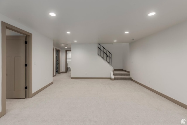 finished below grade area featuring recessed lighting, light carpet, baseboards, and stairway