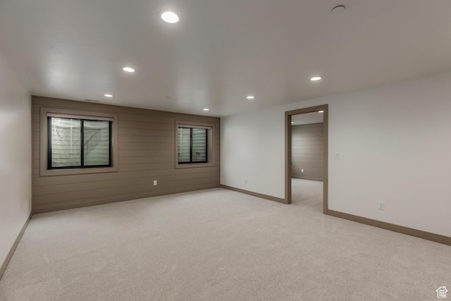 spare room featuring recessed lighting, light colored carpet, baseboards, and wood walls