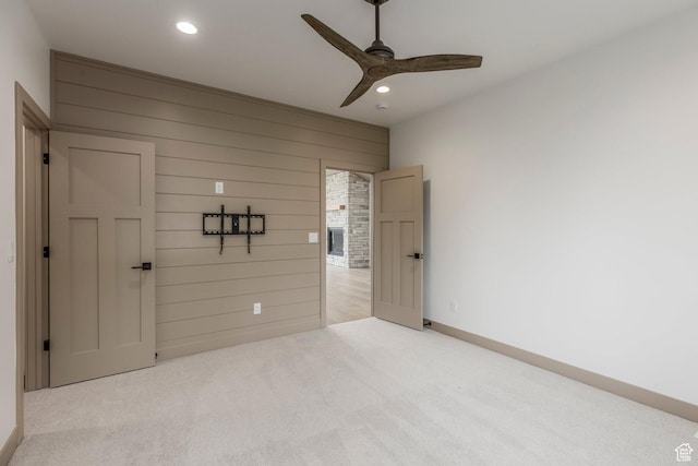 unfurnished bedroom featuring carpet, recessed lighting, wood walls, baseboards, and a ceiling fan