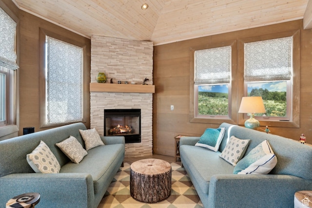 living area featuring healthy amount of natural light, wooden ceiling, lofted ceiling, and a stone fireplace