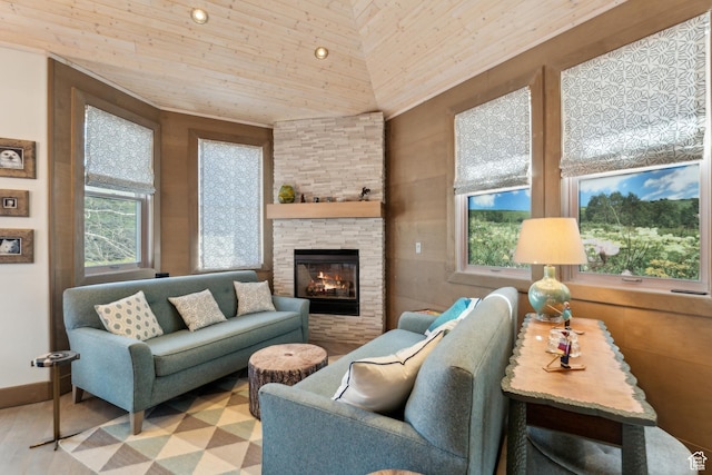 living room with healthy amount of natural light, wood ceiling, a stone fireplace, and wood finished floors