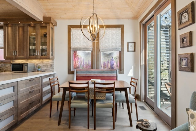 dining space with wood finished floors, plenty of natural light, wooden ceiling, a chandelier, and vaulted ceiling