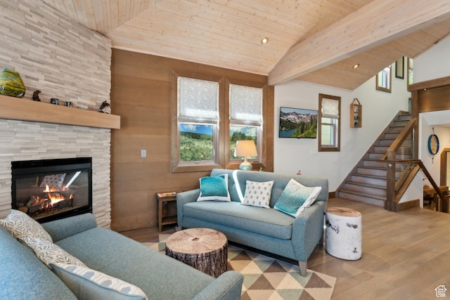 living room featuring wood ceiling, wood finished floors, stairs, a stone fireplace, and high vaulted ceiling