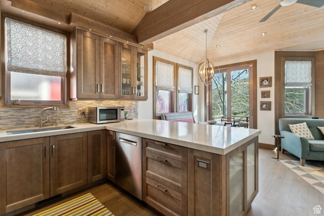 kitchen featuring lofted ceiling, a sink, appliances with stainless steel finishes, wood ceiling, and a peninsula