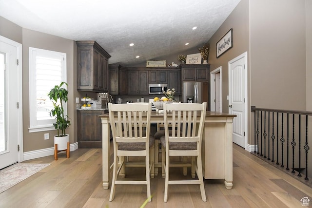 dining space with light wood-type flooring, vaulted ceiling, baseboards, and recessed lighting