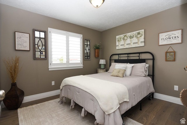bedroom with baseboards, wood finished floors, and a textured ceiling