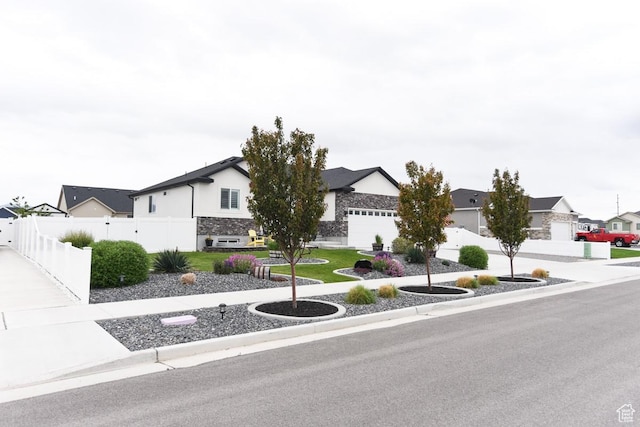 view of front facade featuring fence, a residential view, stone siding, and stucco siding