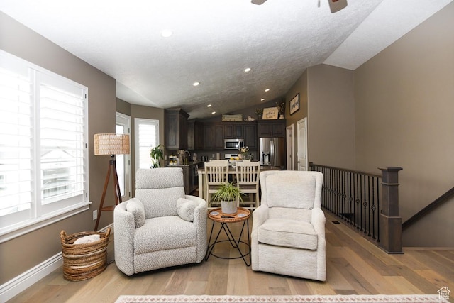 living area with vaulted ceiling, light wood-style floors, baseboards, ceiling fan, and recessed lighting