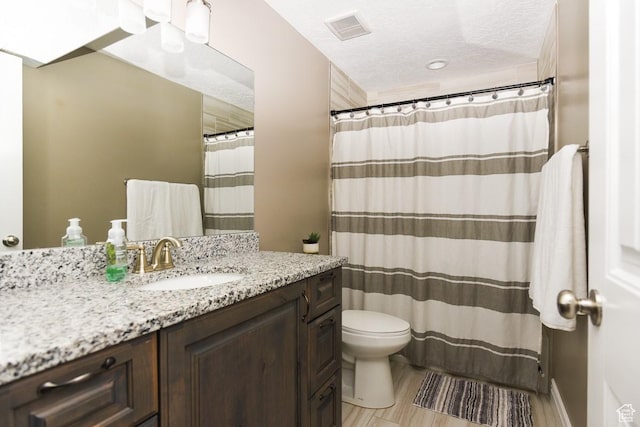 bathroom featuring toilet, vanity, a textured ceiling, and curtained shower