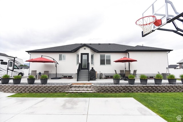 back of house with entry steps, a patio, stucco siding, a yard, and central AC