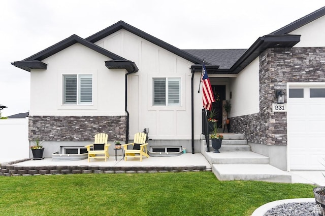 view of exterior entry featuring stone siding, a yard, an attached garage, and stucco siding