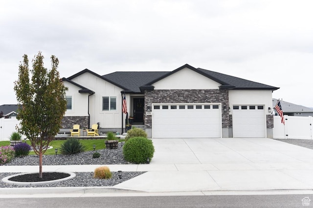 view of front of house with a garage, stone siding, concrete driveway, fence, and a gate