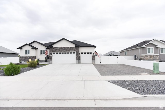 view of front of property with stone siding, an attached garage, fence, and concrete driveway
