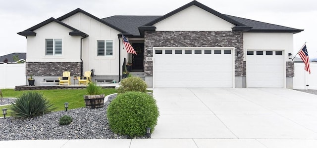 view of front of home featuring a garage, driveway, stone siding, and stucco siding