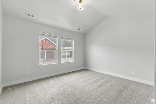 carpeted spare room with vaulted ceiling and baseboards