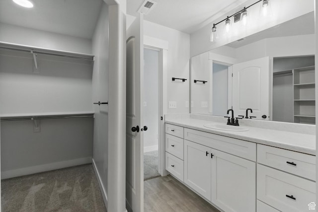 bathroom with a spacious closet, vanity, and baseboards