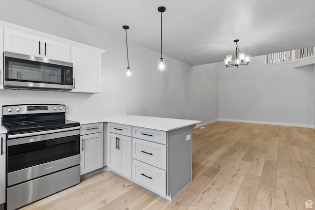 kitchen with appliances with stainless steel finishes, a peninsula, a chandelier, and light countertops