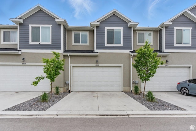 view of property with stucco siding, an attached garage, and concrete driveway