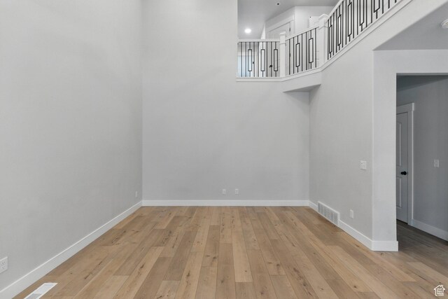 unfurnished dining area featuring hardwood / wood-style flooring, baseboards, and a high ceiling