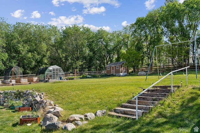 view of yard featuring an outbuilding, a greenhouse, and a vegetable garden