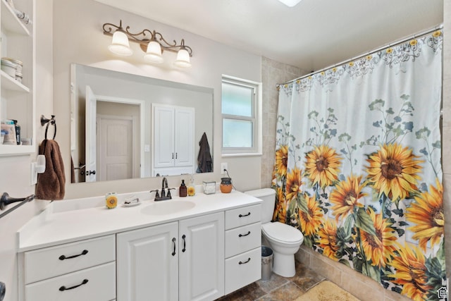 bathroom featuring toilet, vanity, a shower with curtain, and stone finish flooring