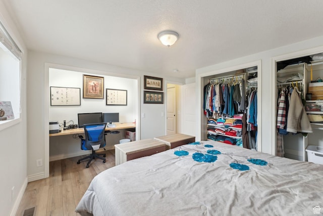 bedroom with two closets, wood finished floors, and baseboards