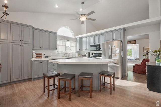 kitchen featuring stainless steel appliances, gray cabinets, high vaulted ceiling, light wood-style floors, and ceiling fan