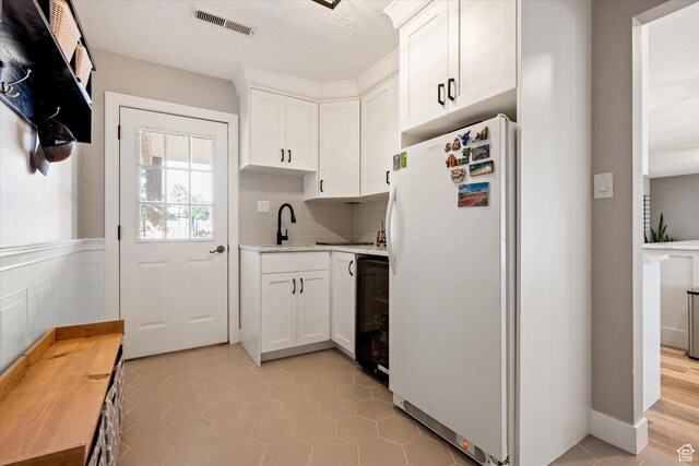 851 E Posado St, Ivins, UT 84738 - kitchen featuring freestanding refrigerator, light countertops, a sink, white cabinetry, and backsplash