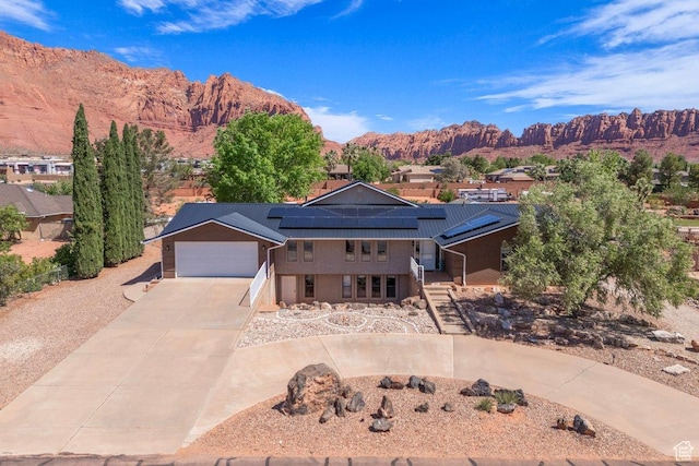 851 E Posado St, Ivins, UT 84738 - view of front facade with concrete driveway, a garage, a mountain view, solar panels, and metal roof