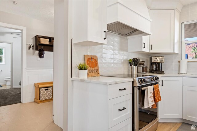 851 E Posado St, Ivins, UT 84738 - kitchen featuring stainless steel electric stove, custom exhaust hood, decorative backsplash, and white cabinets