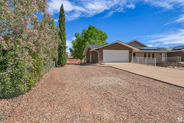 851 E Posado St, Ivins, UT 84738 - view of front of home with driveway, a garage, fence, brick siding, and solar panels