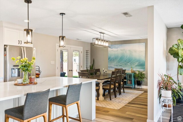 851 E Posado St, Ivins, UT 84738 - kitchen with stainless steel refrigerator with ice dispenser, light wood-type flooring, a breakfast bar area, white cabinets, and pendant lighting