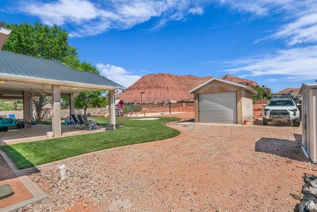 851 E Posado St, Ivins, UT 84738 - view of yard featuring a playground, an outdoor structure, a mountain view, a ceiling fan, and a garage