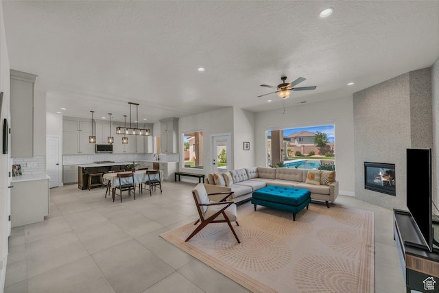 2938 S Poplar Ln, St George, UT 84790 - living room featuring recessed lighting, a ceiling fan, a fireplace, light tile patterned floors, and a textured ceiling