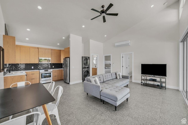 2938 S Poplar Ln, St George, UT 84790 - living room with estacked washer and dryer, a wall unit AC, baseboards, ceiling fan, and a towering ceiling