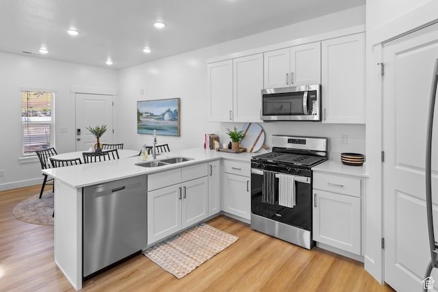 247 W 925 N Unit I49, Brigham City, UT 84302 - kitchen with appliances with stainless steel finishes, a sink, a peninsula, light wood finished floors, and light countertops