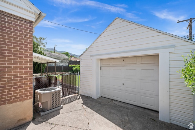 detached garage featuring central air condition unit, fence, a mountain view, and driveway