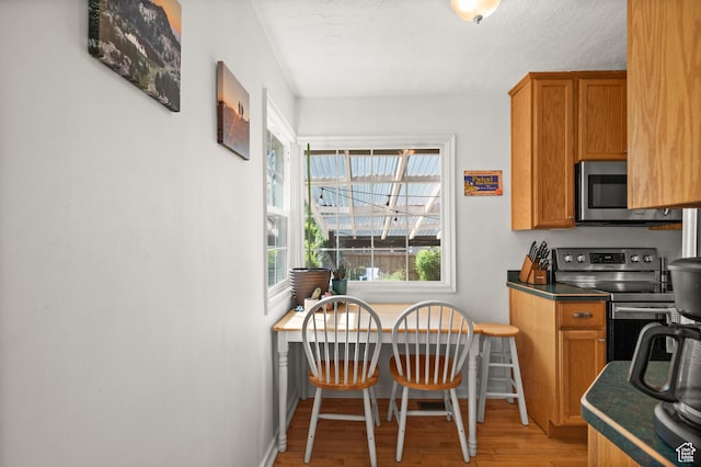 kitchen with stainless steel appliances, light wood-style floors, baseboards, and brown cabinetry